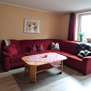 Un salon avec un canapé rouge, une table basse en bois et un tableau encadré accroché au mur.