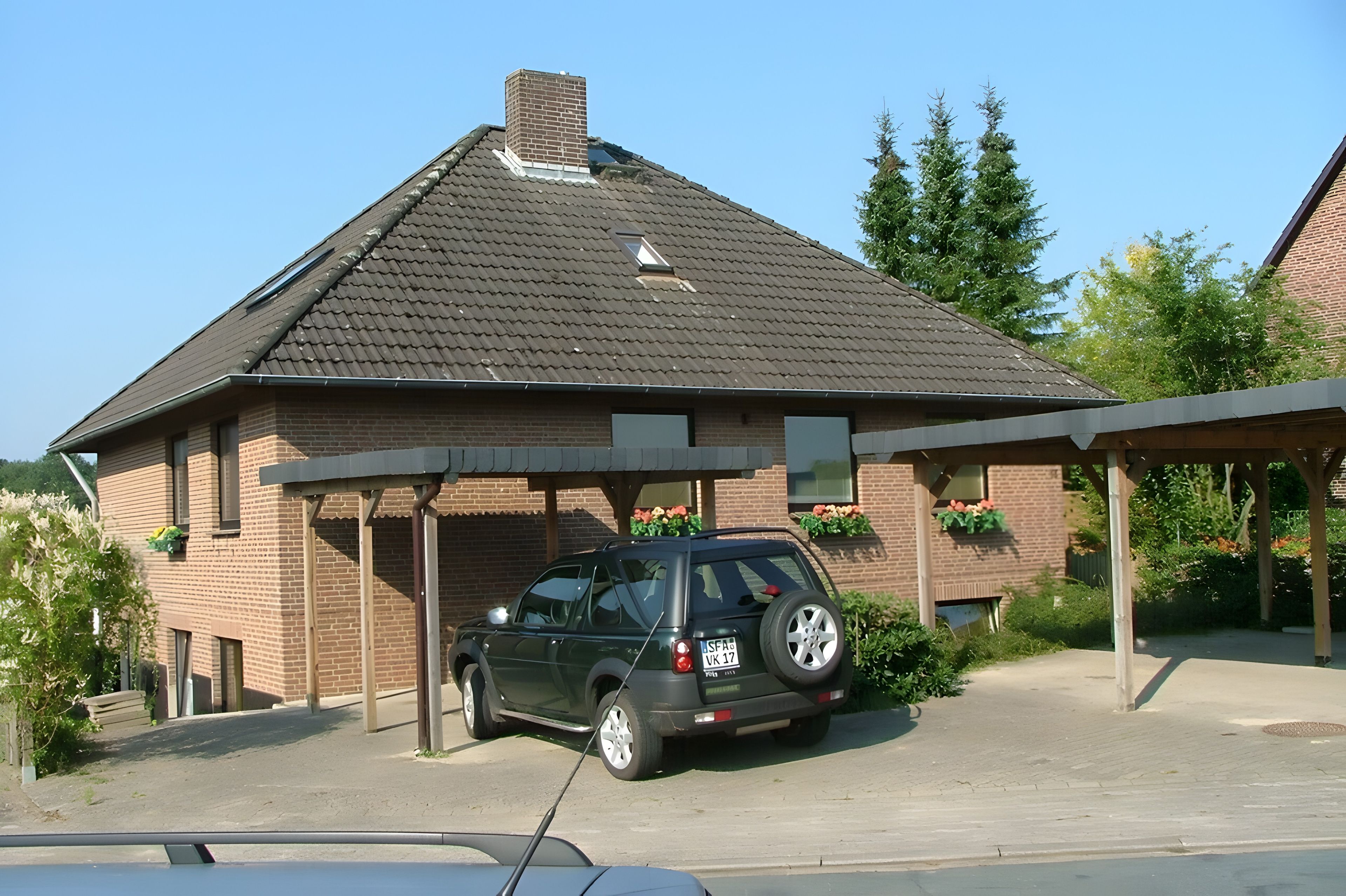 Ein Backsteinhaus mit geneigtem Dach und einem überdachten Parkbereich.