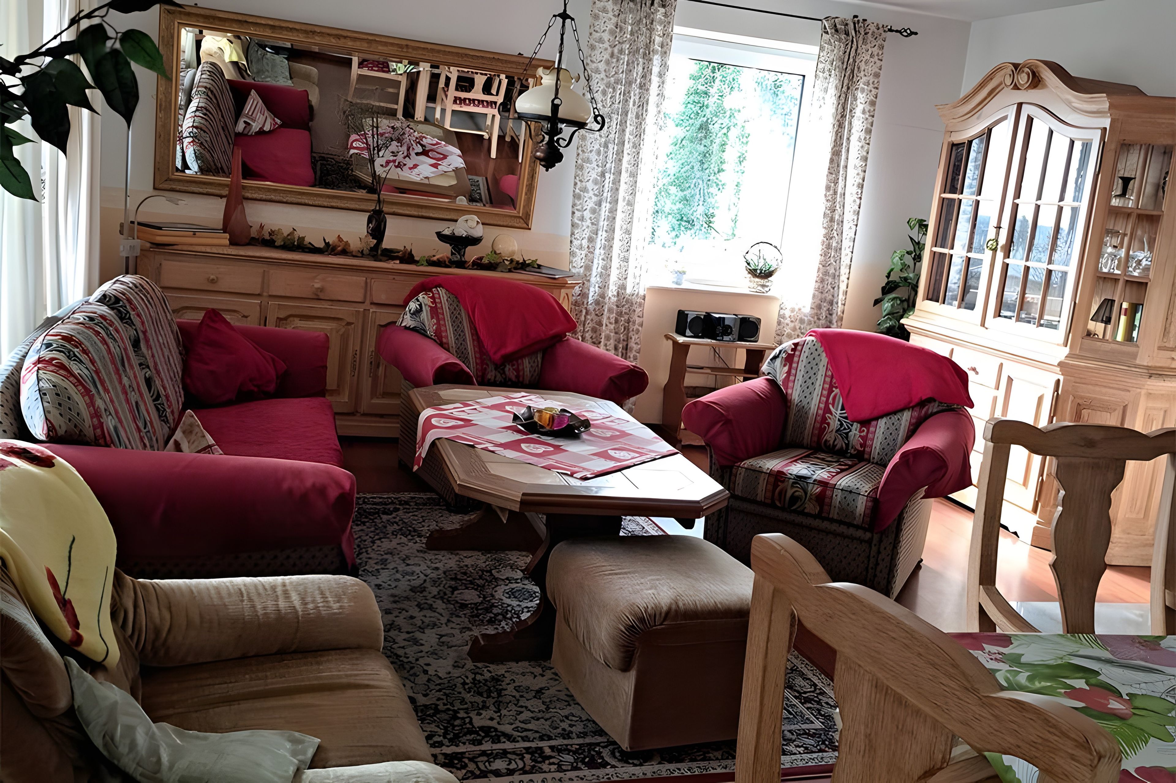 Ein gemütliches Wohnzimmer mit einer Couch, Sesseln, einem Couchtisch und einem Schrank.