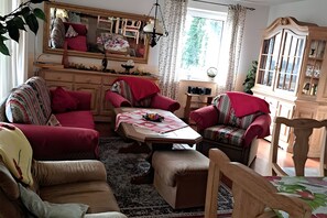 Un salon confortable avec un canapé, des fauteuils, une table basse et un meuble.