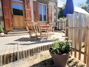 Une terrasse en bois avec des meubles d’extérieur, une plante en pot et une clôture en bois.