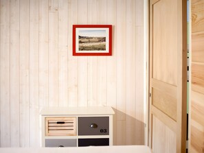 A room with a wooden wall, a framed picture, a cabinet with drawers, and a door.