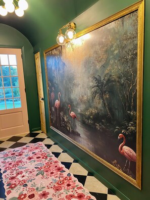 A room with a large painting of flamingos, a checkered floor, and a floral-patterned rug. - The Kallie Cottage (Trenton)