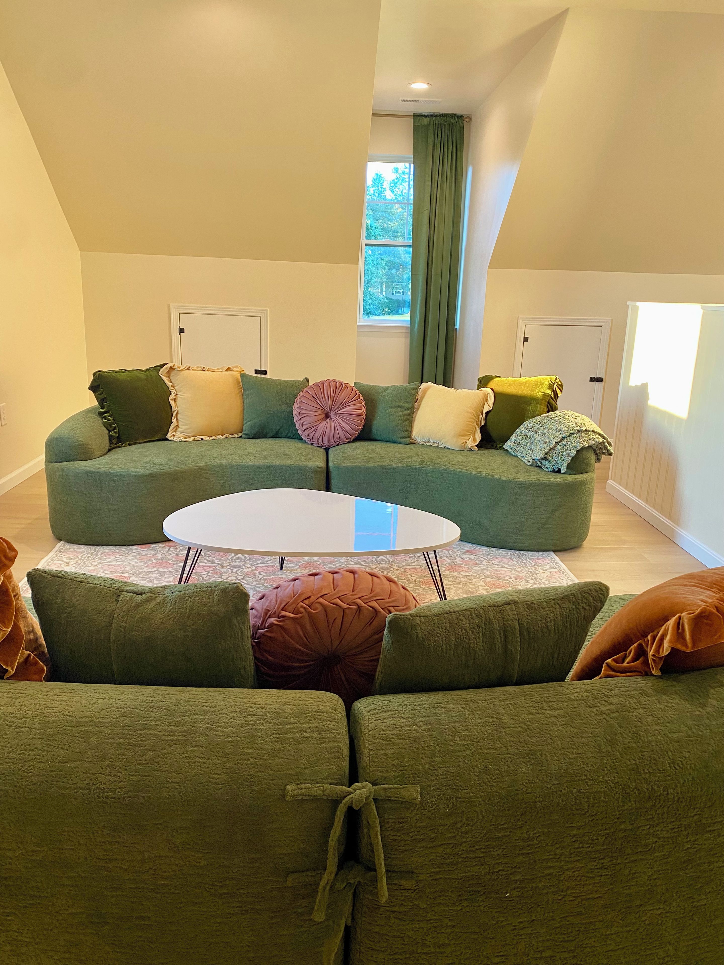 A living room with a sectional sofa, a round coffee table, and a view of the outdoors through a window.