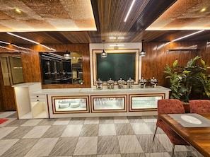 A modern hotel lobby with a central bar area, a large mirror, and a potted plant. - OnlyStay Veda Inn Ayodhya (Faizabad)
