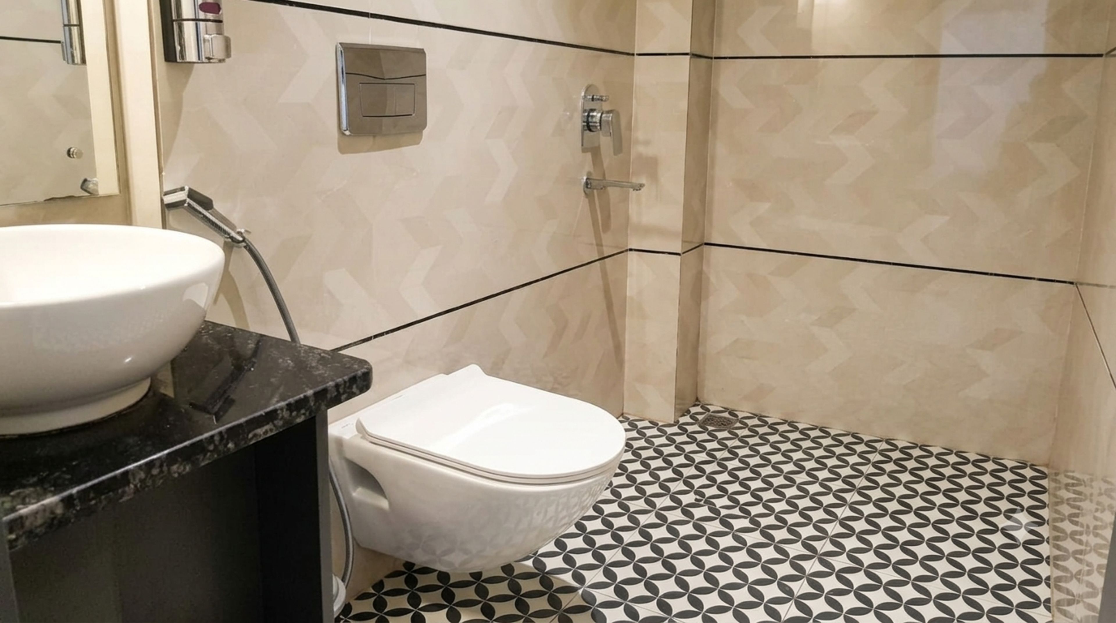 A bathroom with a white toilet, a sink with a black countertop, and a shower area with patterned tiles.