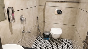 A bathroom with a toilet, a bidet, and a shower area. - OnlyStay Veda Inn Ayodhya (Faizabad)
