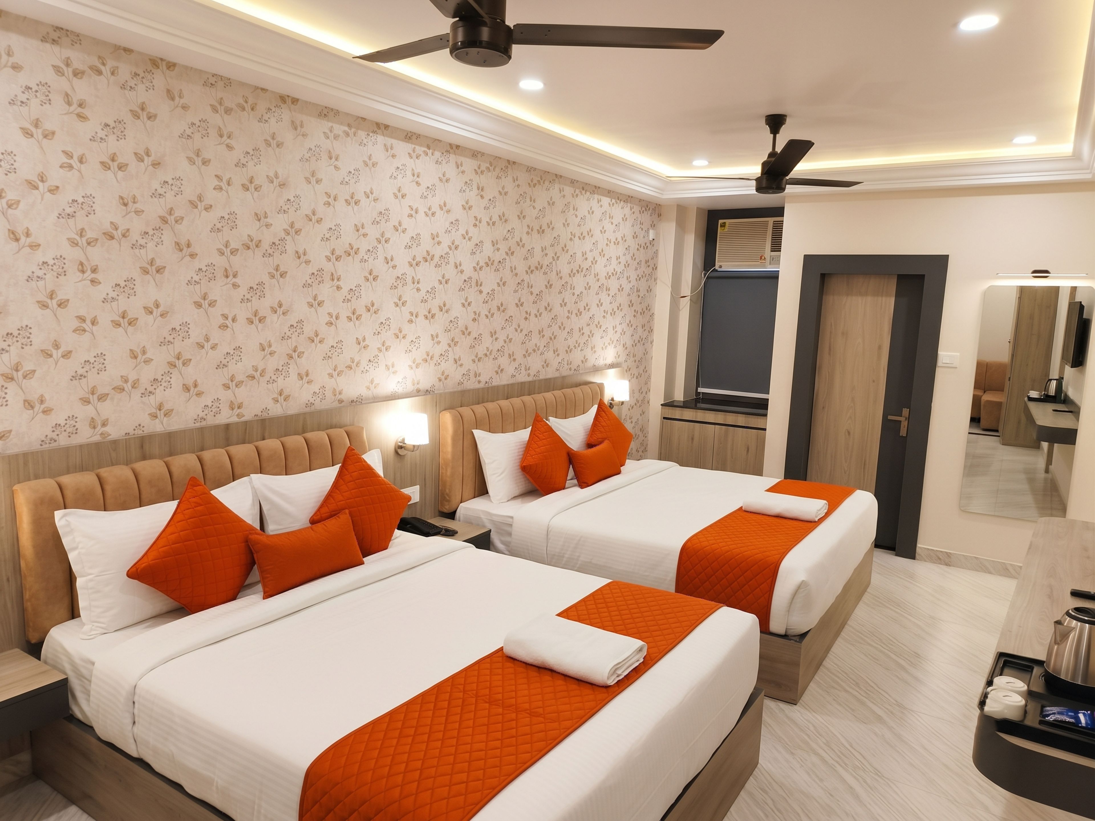 A hotel room with two beds, a ceiling fan, a mirror, and a bathroom visible through an open door.