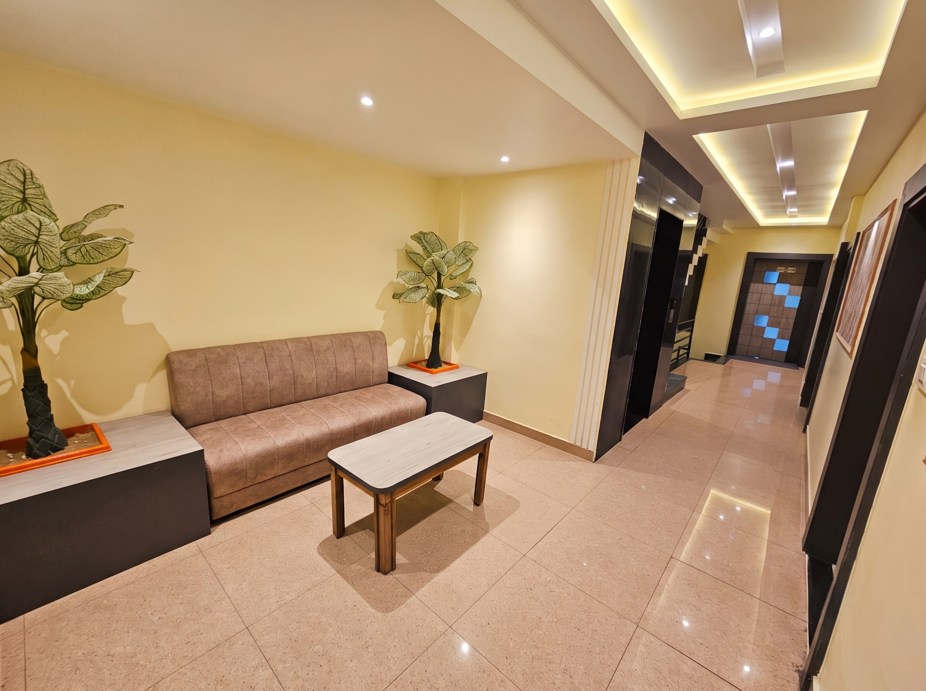 A hotel lobby with a sofa, a coffee table, and two potted plants.
