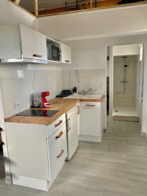 Eine moderne Küche mit weißen Schränken, einer Holz Arbeitsplatte und einer eingebauten Mikrowelle.