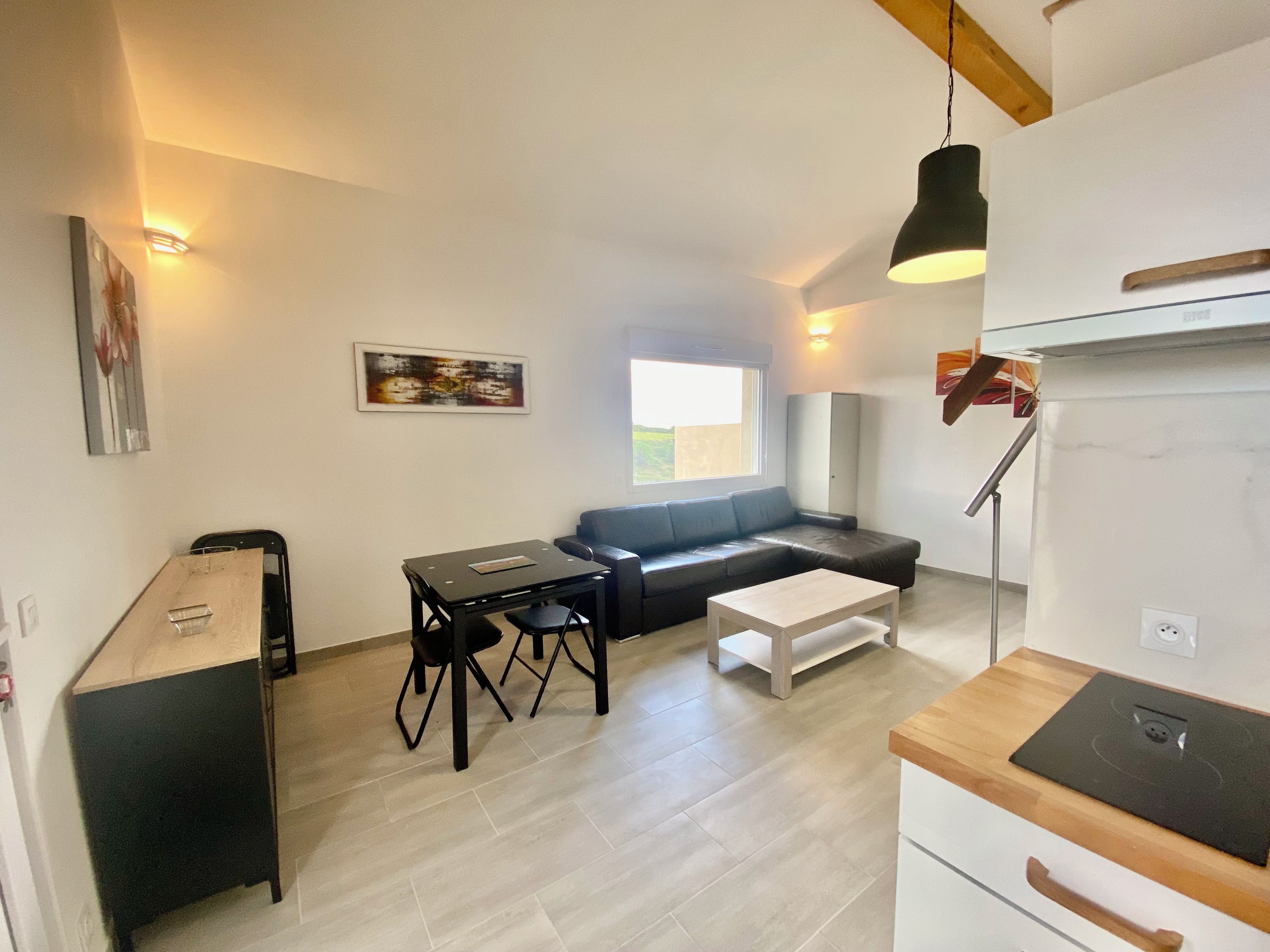 A modern living room with a sofa, a dining table, and a kitchen area with a stove.