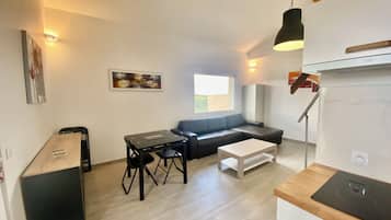 A modern living room with a sofa, a dining table, and a kitchen area with a stove.
