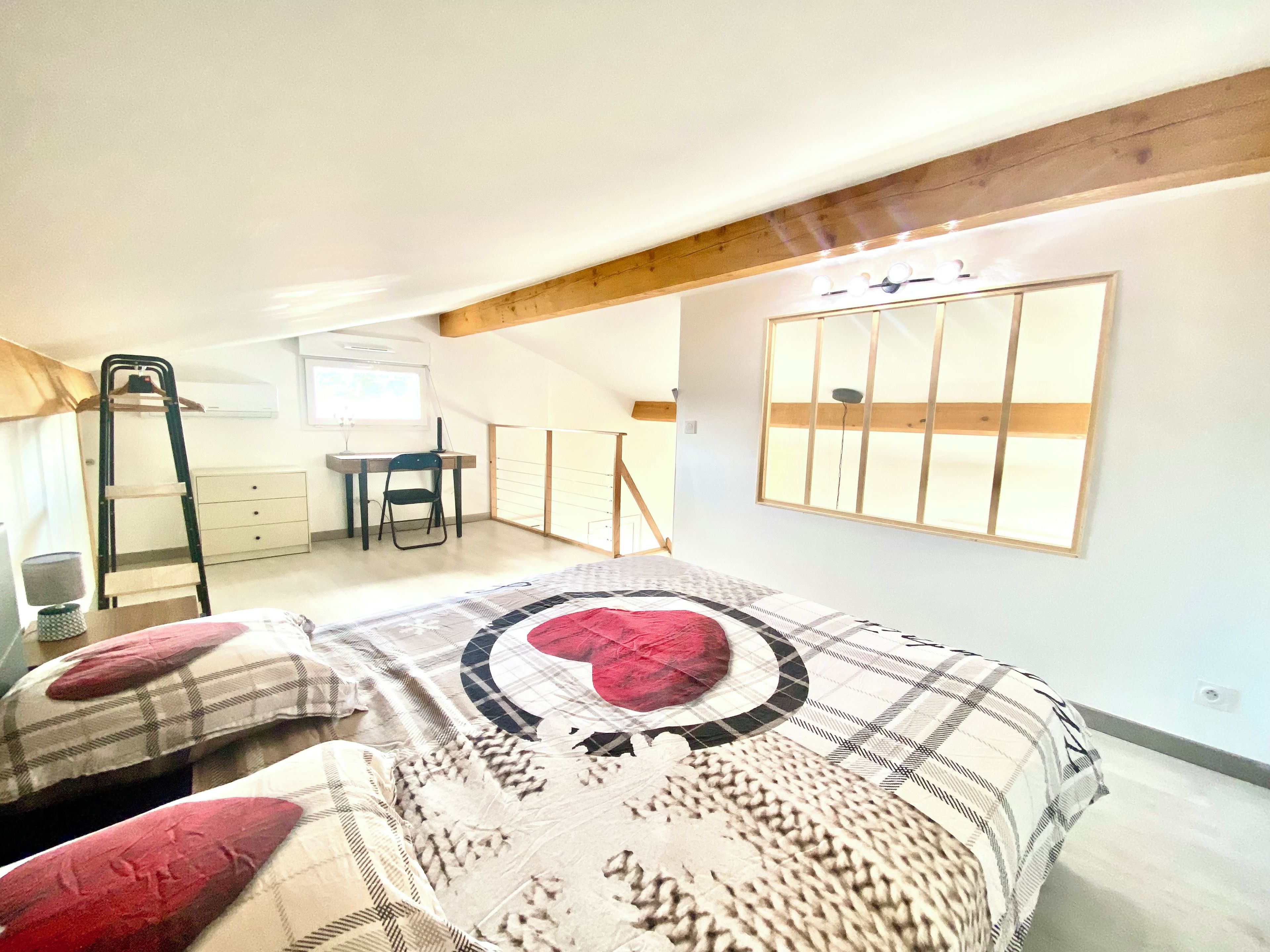 Une chambre à coucher avec un lit, un bureau, une chaise et une échelle.