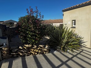 A courtyard with a stone wall, a tree with red leaves, and a building with a tiled roof. - New Listing (Aragon)