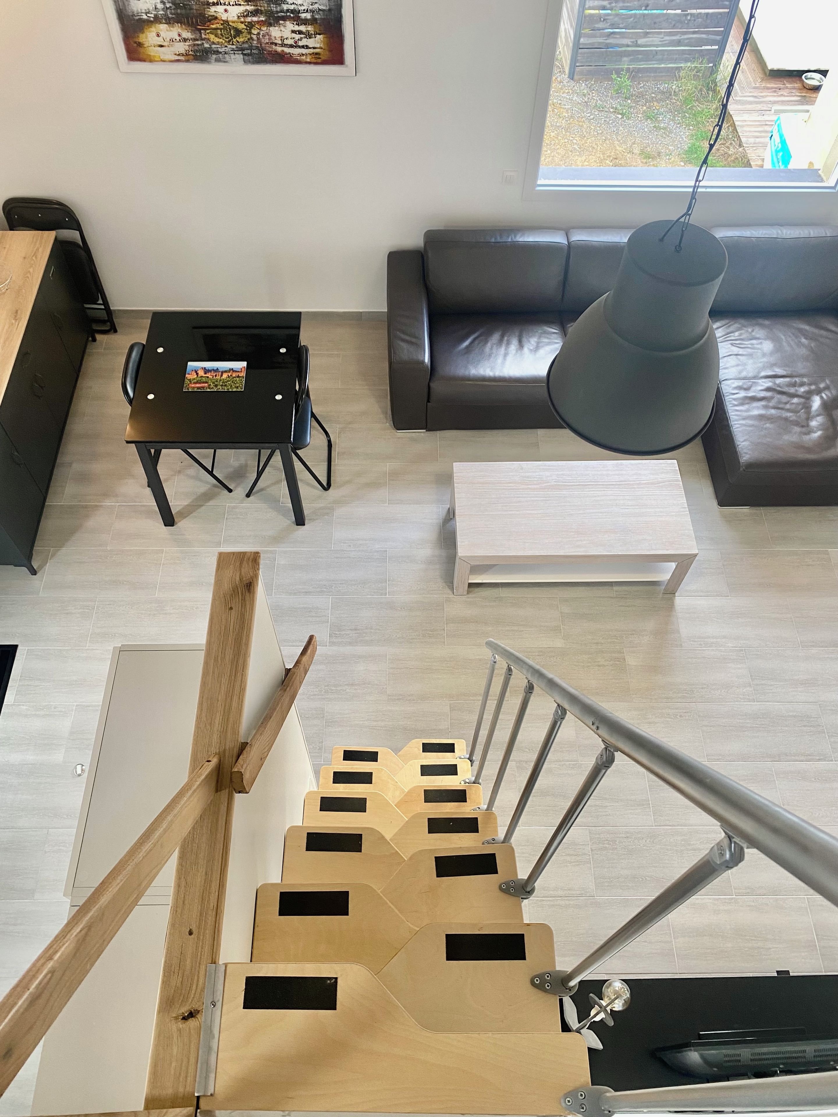 A modern living room with a sofa, a dining table, and a staircase.