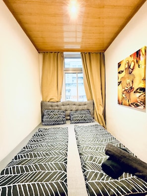 A narrow room with a bed, a window with curtains, and a painting on the wall. - A Little Vienna Private Room near FAC (Wien)