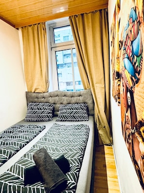A bed with patterned bedding, a window with curtains, and a wall with a colorful mural. - A Little Vienna Private Room near FAC (Wien)