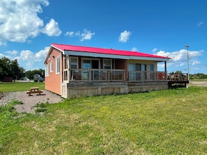 A single-story building with a red roof, a covered porch, and a picnic table in front.