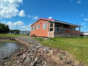 Un edificio de dos pisos con techo rojo y una terraza de madera.