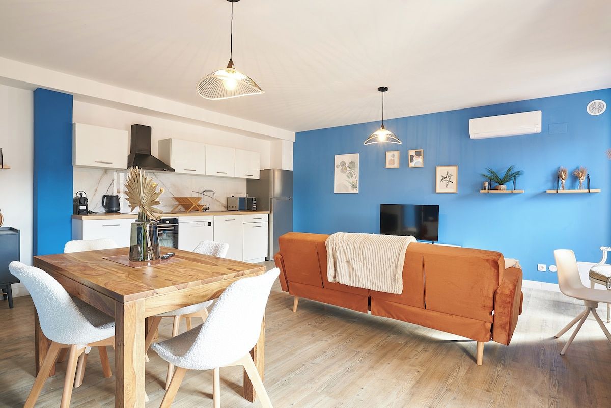 Una cucina moderna con mobili bianchi, un tavolo da pranzo in legno e una parete azzurra.