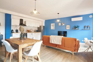 Una cucina moderna con mobili bianchi, un tavolo da pranzo in legno e una parete azzurra.