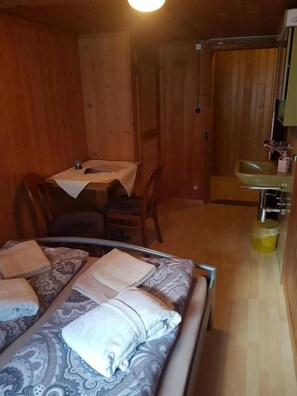 A room with a bed, a table with chairs, a sink, and a mirror. - Hotel-Restaurant-Linde (GUNDLISCHWAND)