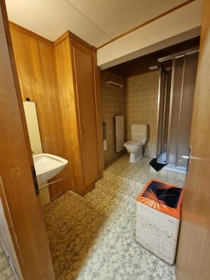 A bathroom with a wooden vanity, a toilet, and a shower area. - Hotel-Restaurant-Linde (GUNDLISCHWAND)