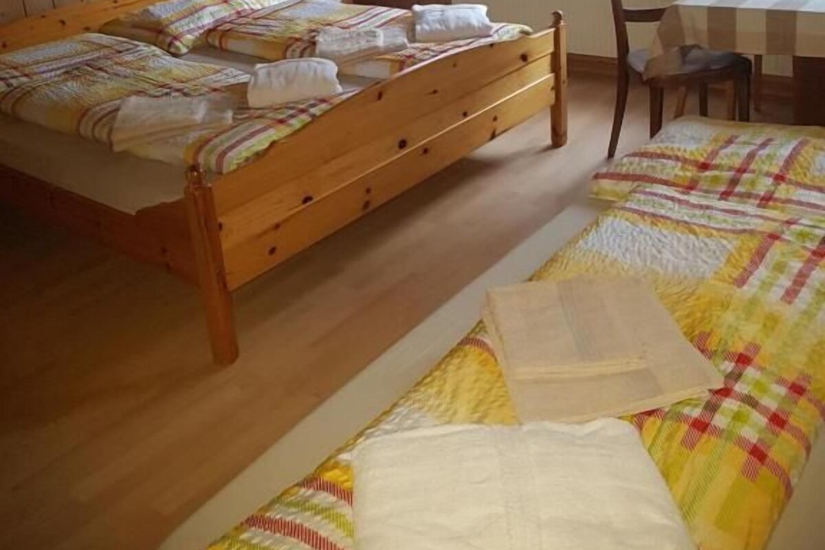 A room with two wooden beds, a table, and chairs.