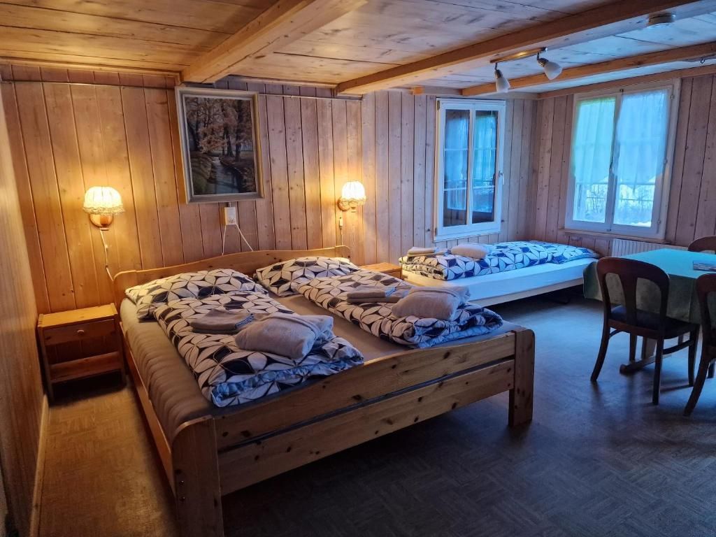 Una habitación de cabaña de madera con dos camas, un escritorio y un ventanal.