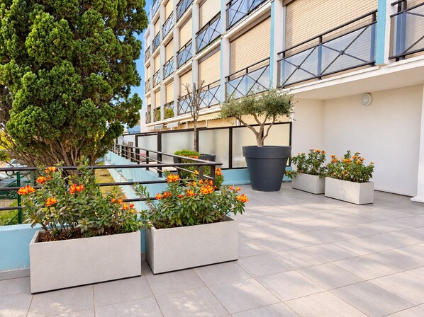 Eine Dachterrasse mit Topfpflanzen, einer Treppe und einer Gebäudefassade.