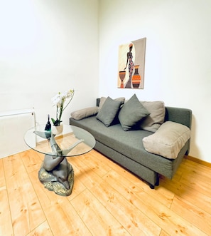 A modern living room with a grey sofa, a glass coffee table, and a painting on the wall. - Hello Vienna Private Room near FAC Platz (Wien)