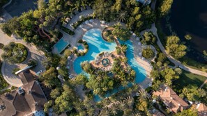 Vista aérea de un complejo turístico con una piscina central, rodeado de zonas ajardinadas y senderos.