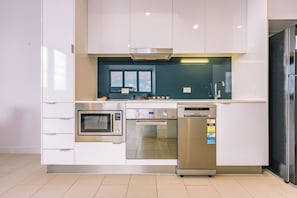 Een moderne keuken met ingebouwde apparatuur, waaronder een magnetron, oven en vaatwasser, met een raam boven de aanrecht.