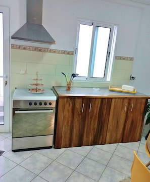 Une cuisine équipée d’une cuisinière, de meubles en bois, d’une fenêtre et d’un pare-feu en carreaux.