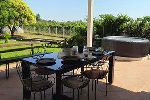 An outdoor patio with a table, chairs, a hot tub, and a garden view. - New Listing (Aprilia)