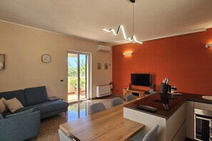 Un saló modern amb un sofà, taula de dinar, televisió i zona de cuina.