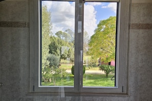 A room with a large window overlooking a garden. - New Listing (Aprilia)