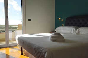 A hotel room with a large bed, a view of the outdoors, and a balcony. - New Listing (Aprilia)