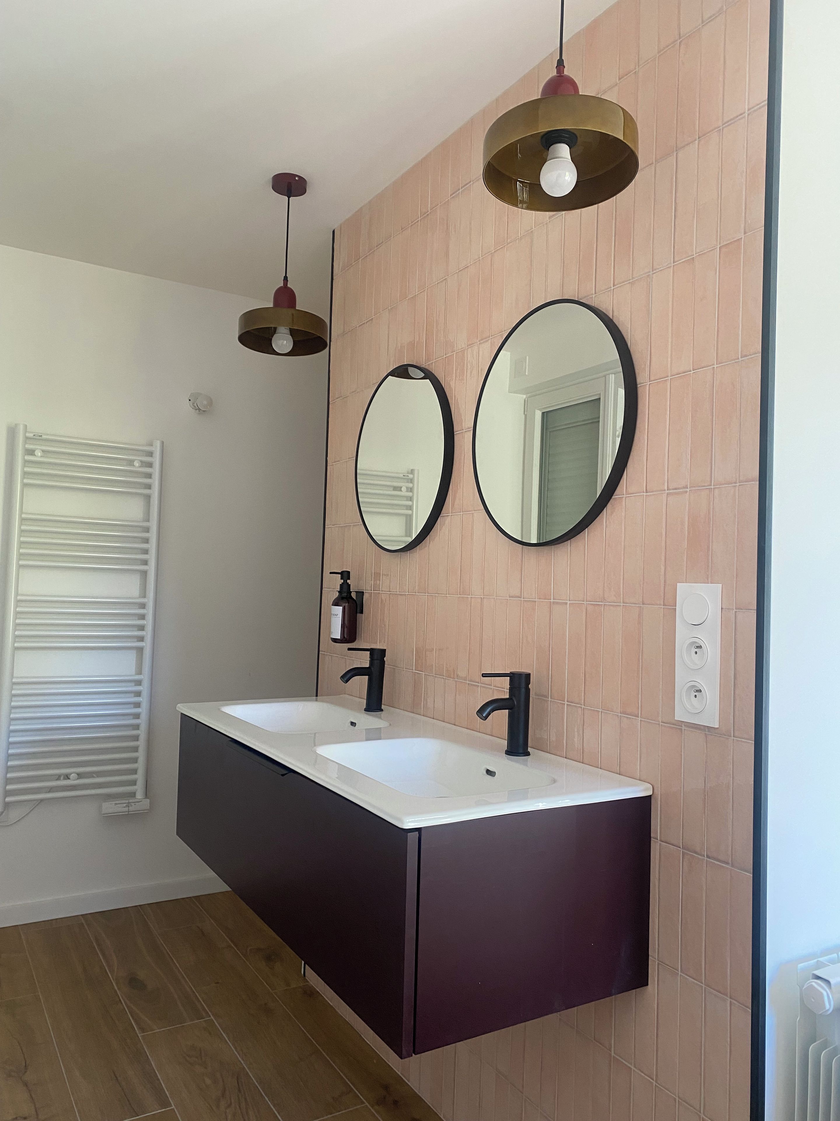 A modern bathroom with two sinks, a towel rack, and a mirror.