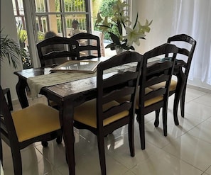 A dining area with a wooden table and chairs, a vase with flowers, and a view of greenery outside. - La Castillada (Villa centra)