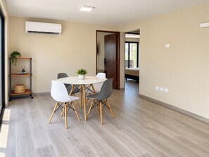 Un comedor con una mesa redonda, cuatro sillas y una planta en maceta.