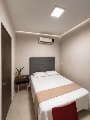 Une chambre à coucher comprenant un lit, une table de chevet et un appareil de climatisation.