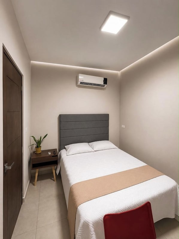 Une chambre à coucher comprenant un lit, une table de chevet et un appareil de climatisation.
