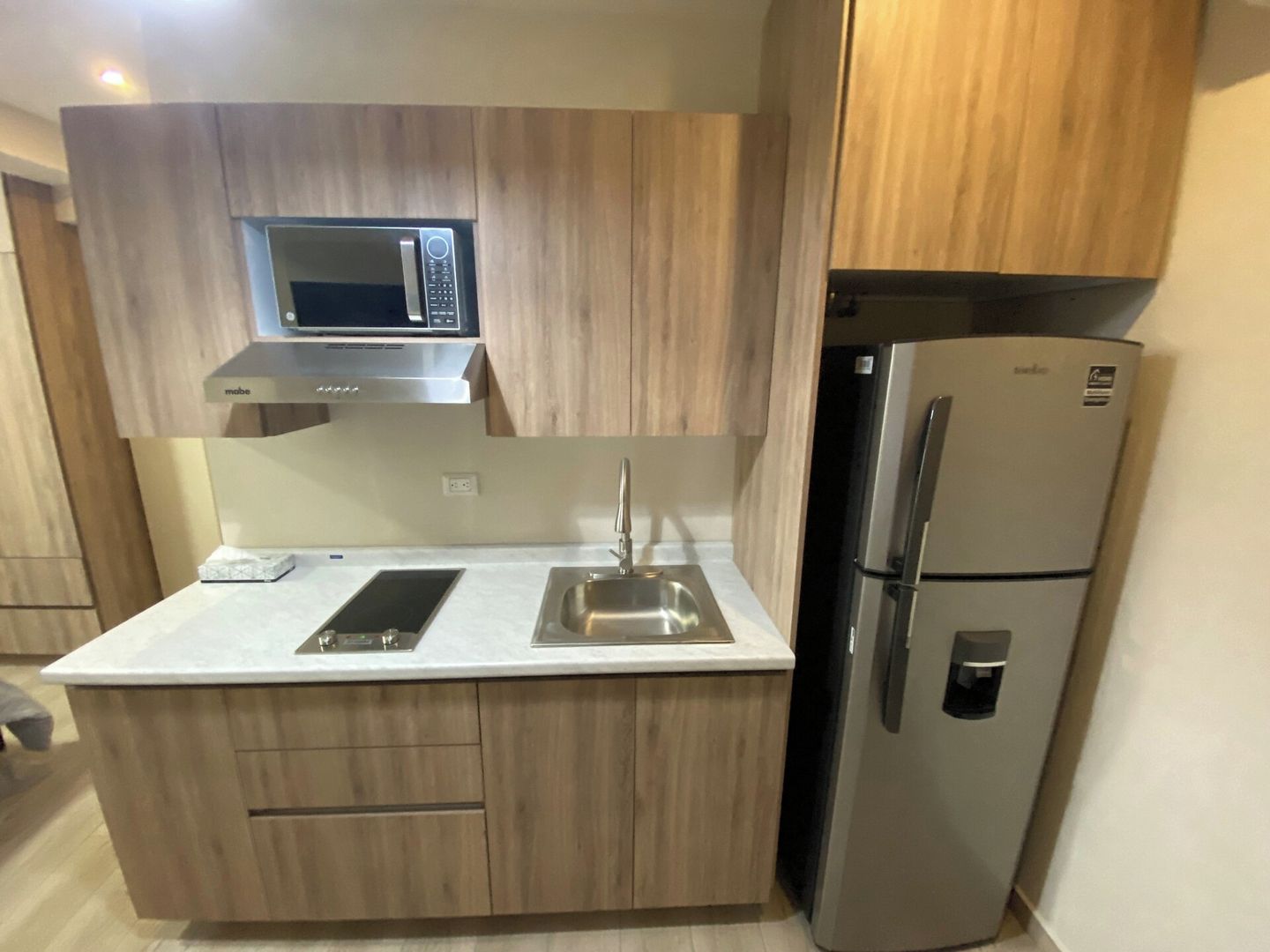 A compact kitchen with a microwave, a refrigerator, and a sink.