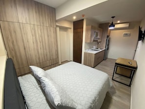 A bedroom with a bed, a bedside table, and a small kitchenette with a sink and a refrigerator. - Enjoy Monterrey from a comfortable, centrally located spot. | SB204 (San Nicolás de los Garza)