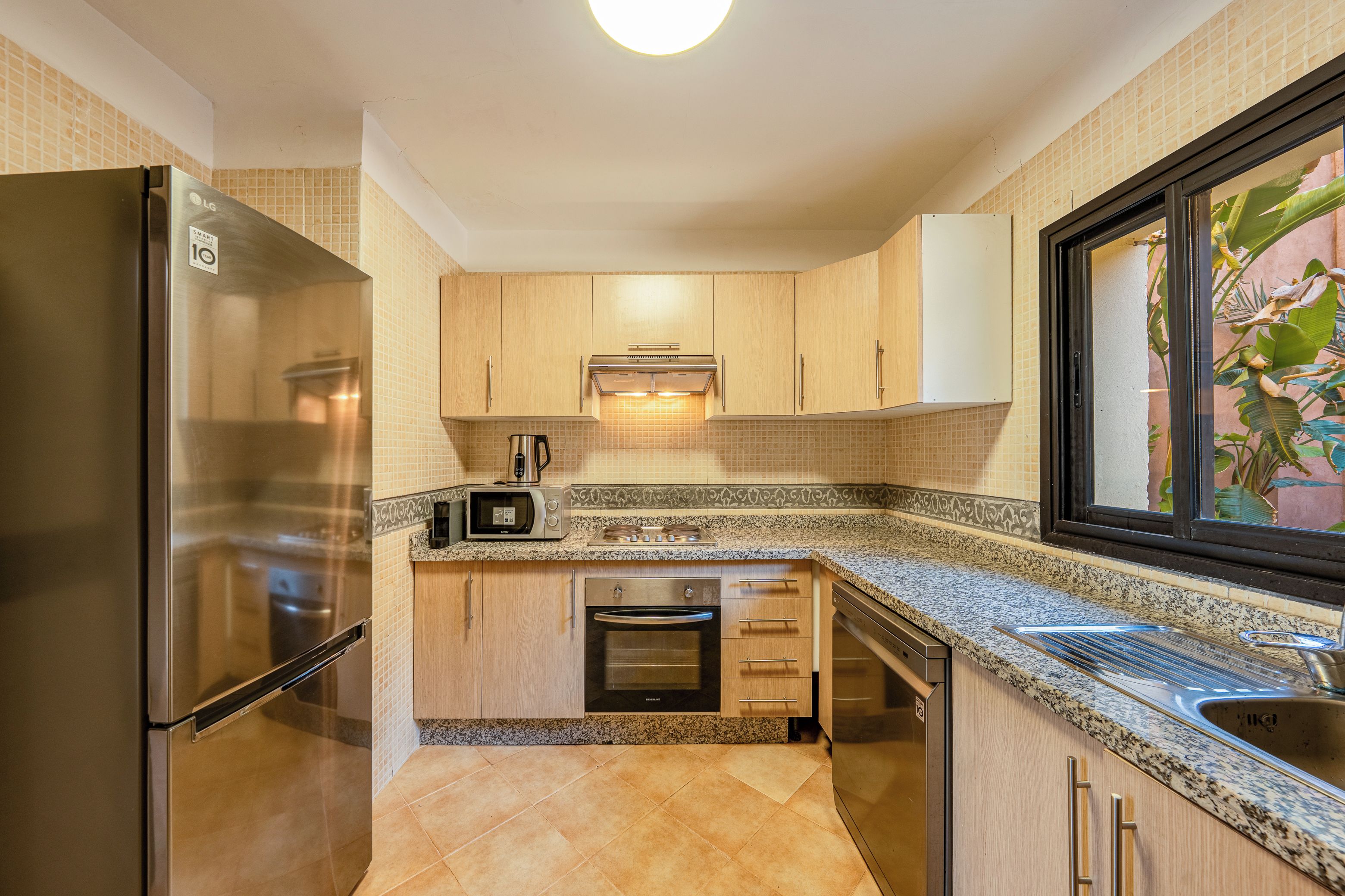 A compact kitchen with a stainless steel refrigerator, a microwave, and a built-in oven.