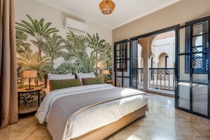 A bedroom with a bed, a nightstand, a lamp, and a large window with a view of an outdoor balcony. - New Listing (Marrakech)