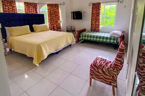 A hotel room with a large bed, a smaller bed, a television, and a giraffe statue. - Thebreeze2022 (St Toolies,  Tollgate, Clarendon Park)