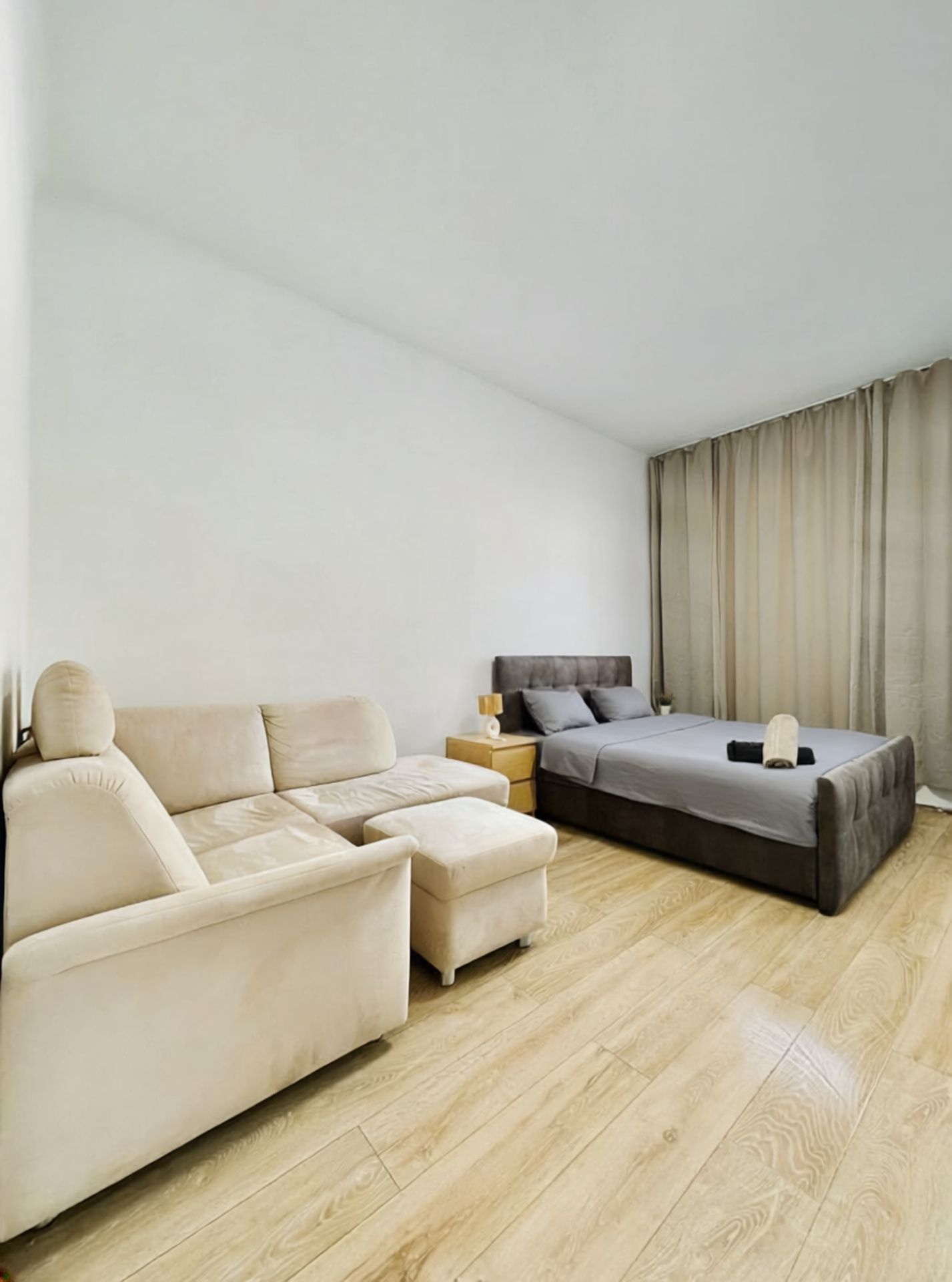 A modern bedroom with a sofa, a bed, and a nightstand.