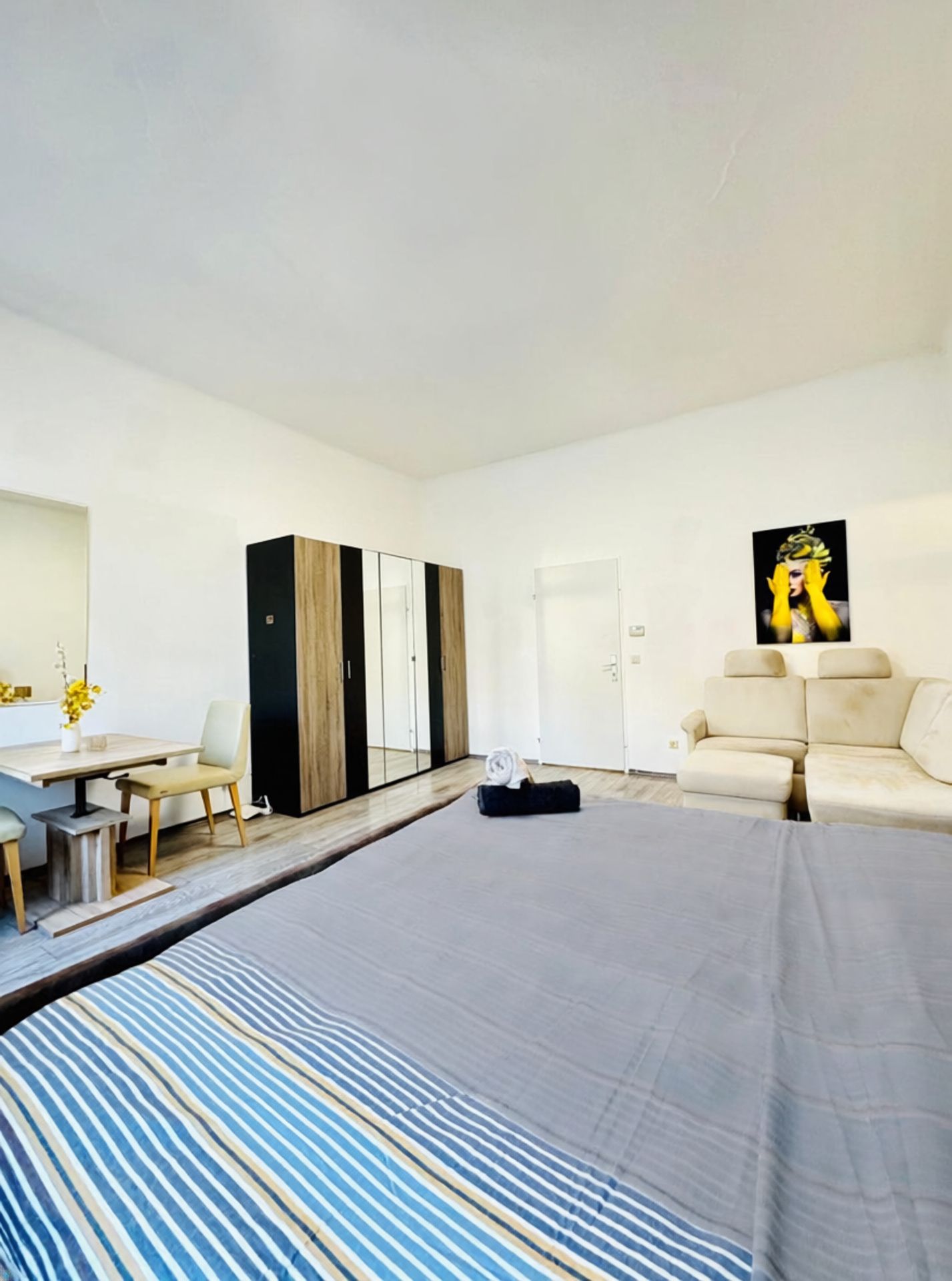Een moderne hotelkamer met een bed, een bureau, een stoel, een kledingkast en een bank.